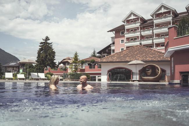Uomo e donna immerse nella piscina esterna della family spa del Cavallino Bianco.